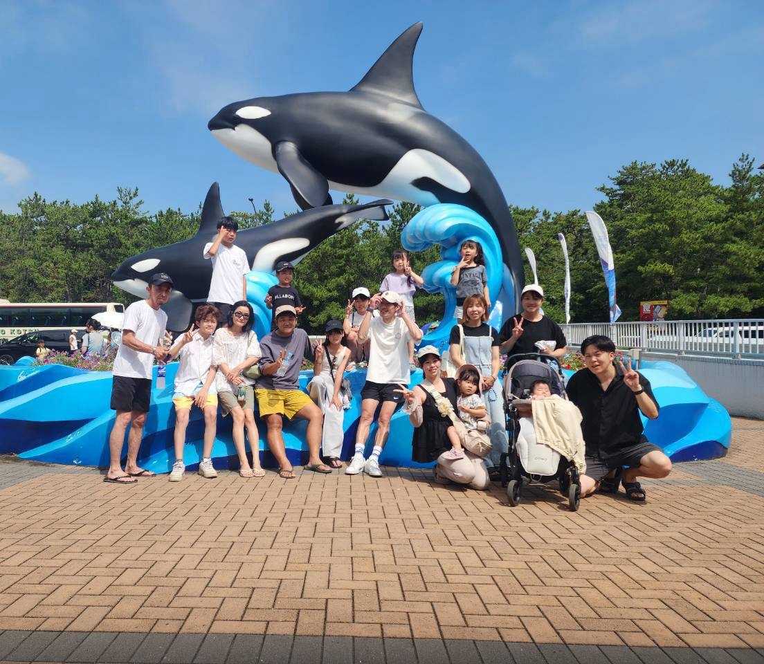 シャチのモニュメントの前に大人と子どもが並ぶ集合写真