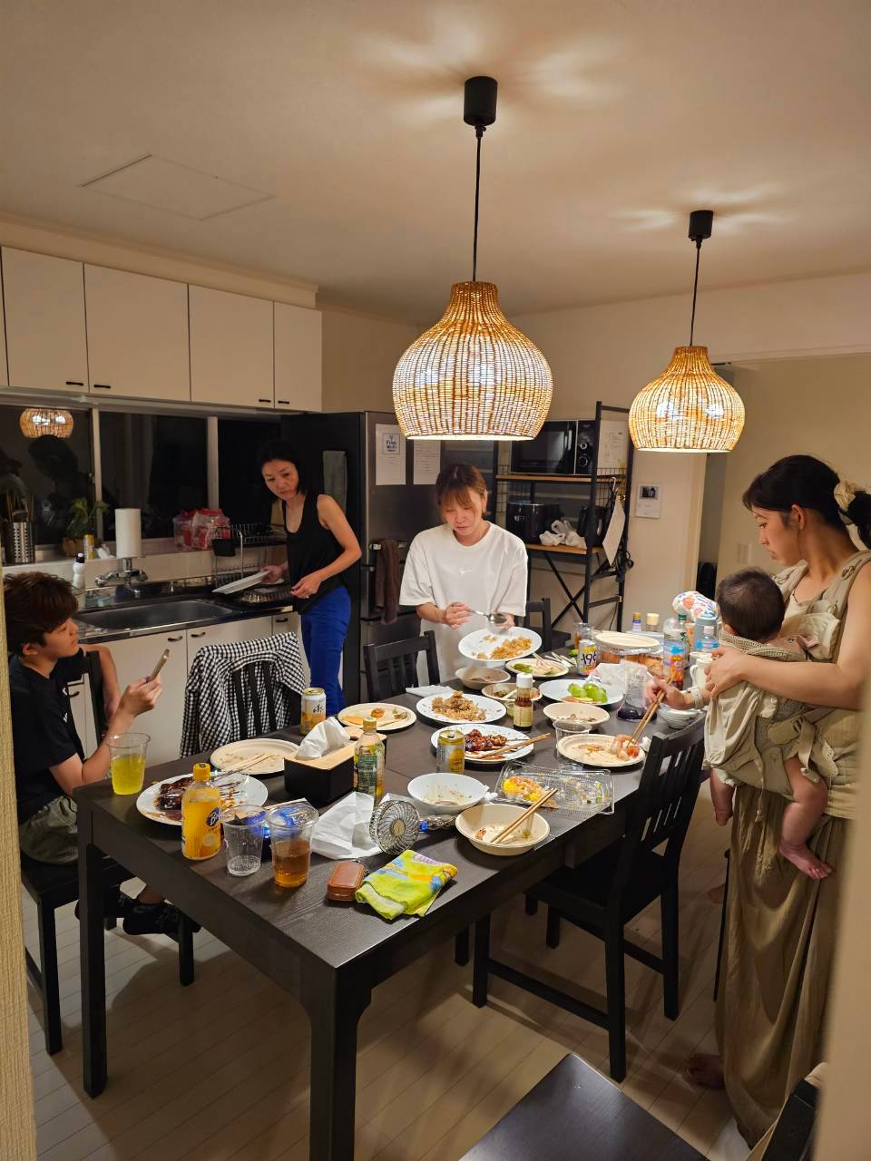 宿の食卓の周りに集まる大人と子どもたち