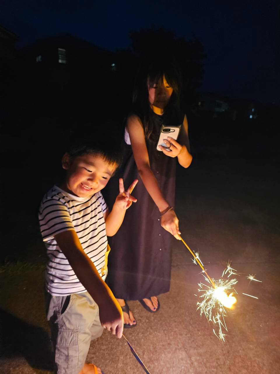 暗い屋外で手持ち花火を楽しむ大人と子ども