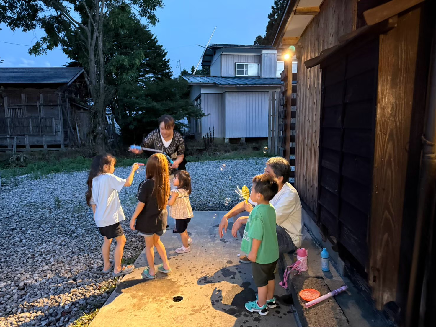 古民家の外で遊ぶ子どもたちと近くの大人